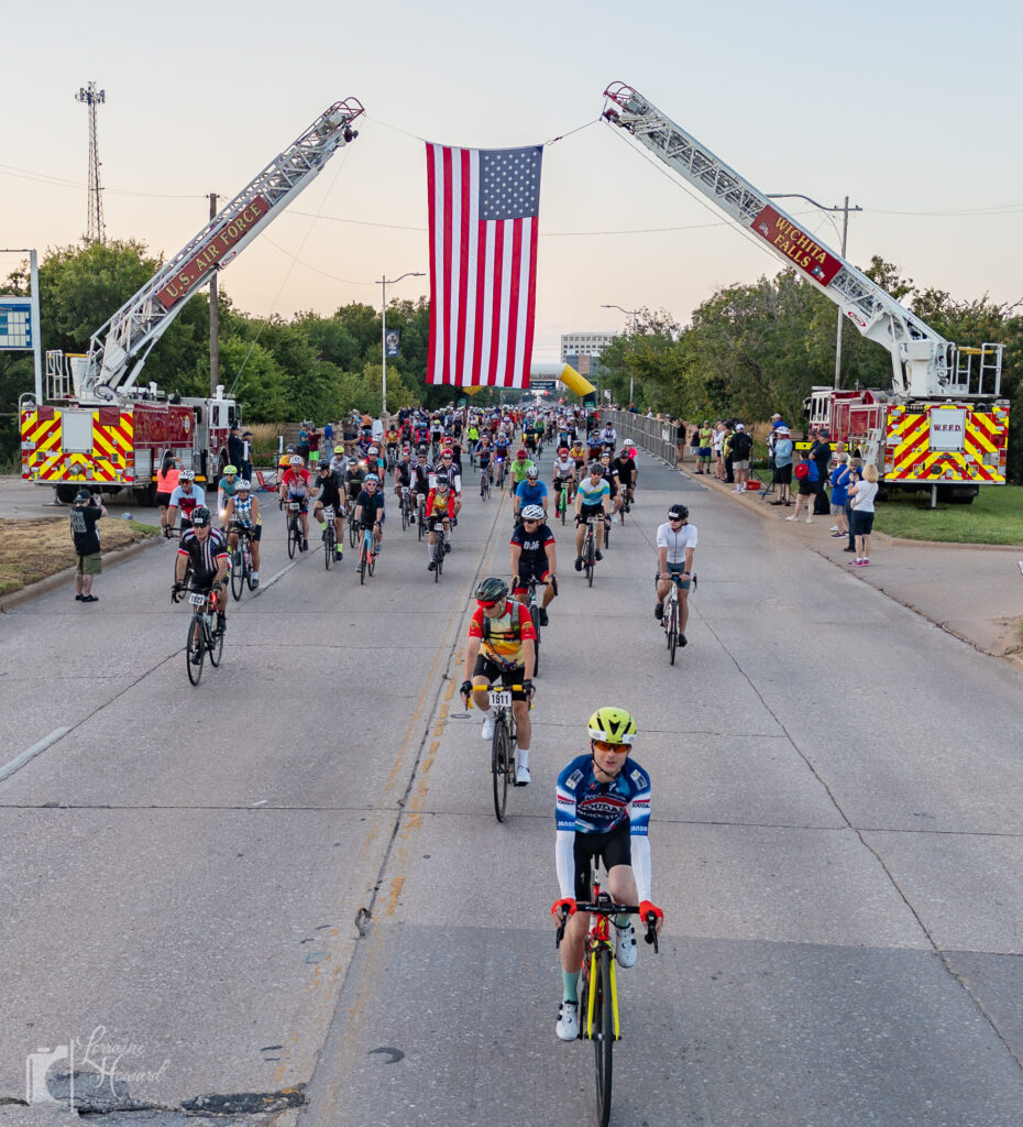 Drone photo of Wichita Falls skyline and Hotter’N Hell Hundred 2025 riders at dawn.