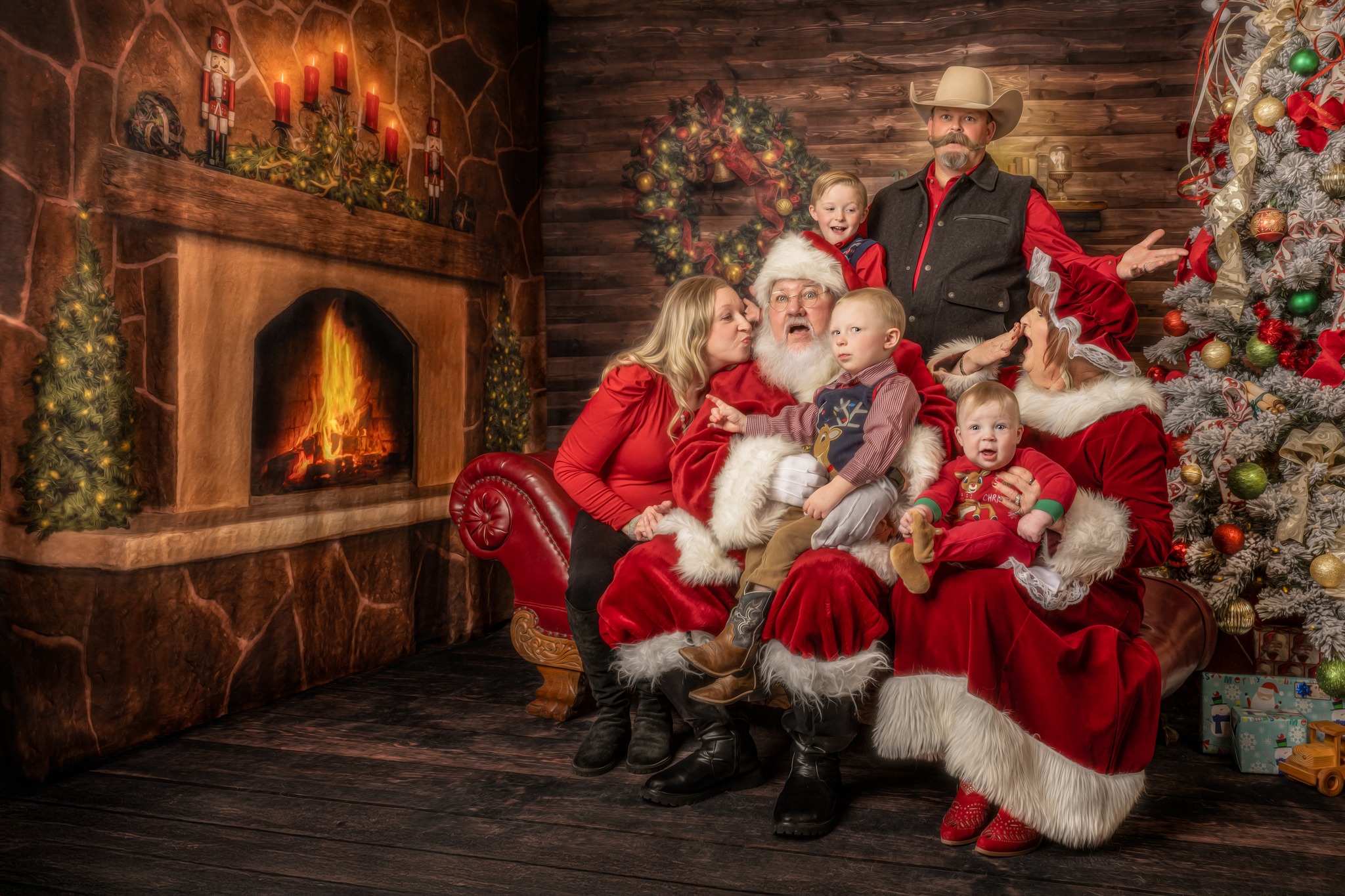 Family gathered with Santa and Mrs. Claus by the Christmas tree and fireplace during Classic Santa Sessions in Wichita Falls